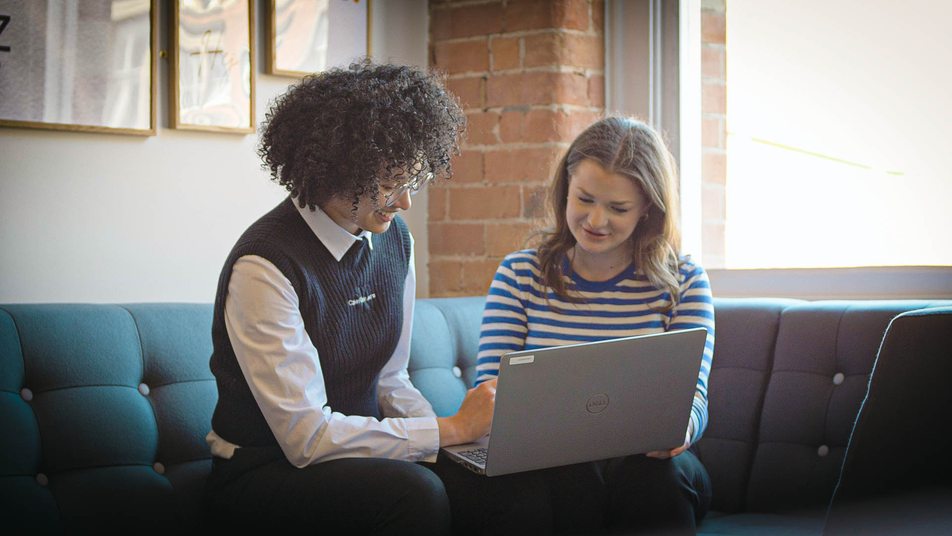 Tamika Gayle and Rose Jinks looking at a laptop on sofas in the EMEA Recruitment office reception area