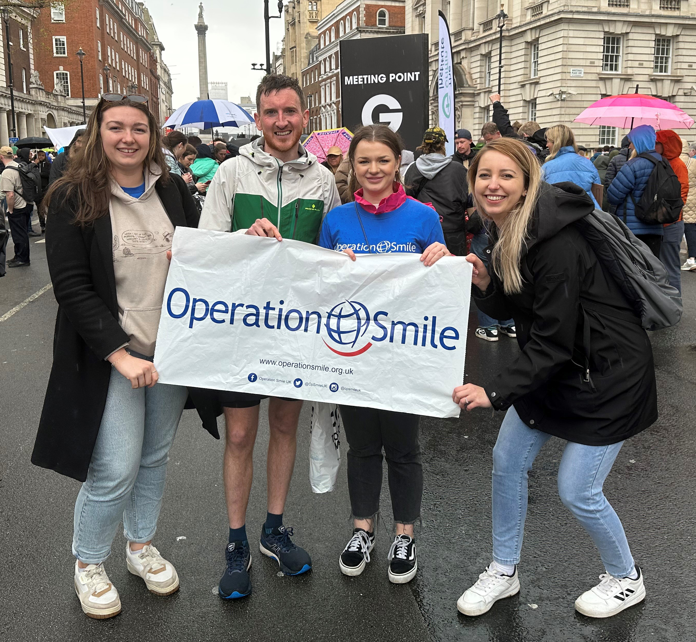 Photograph of Sasha Gill, Neil Cope, Rose Jinks and Neil's partner holding an Operation Smile banner after Neil had finished the London Marathon in April 2023